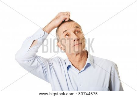 Portrait of confused man scratching his head.