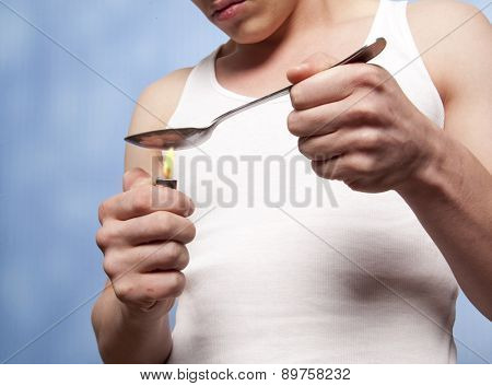 Man with a hardline drug addiction heating drugs in a spoon over a flame 