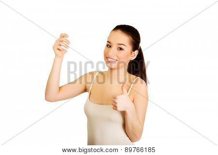 Young smiling woman with anti perspirant and thumbs up.