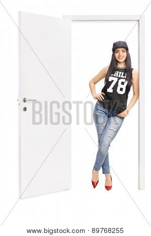 Full length portrait of a young woman in hip hop clothes posing by an open door isolated on white background