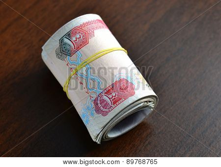 Hundred dirham notes rolled and tied with rubber band.