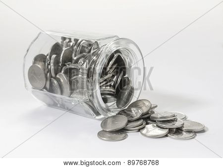 UAE dirham coins spilling out from a glass jar. 
