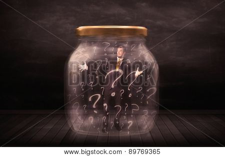 Businessman locked into a jar with question marks concept on background