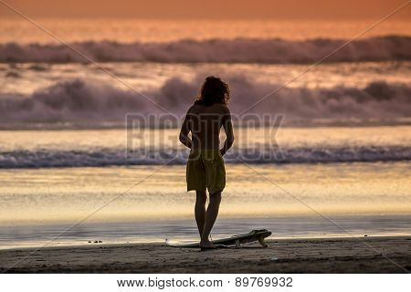 Surfer On The Beach At Sunset Tme