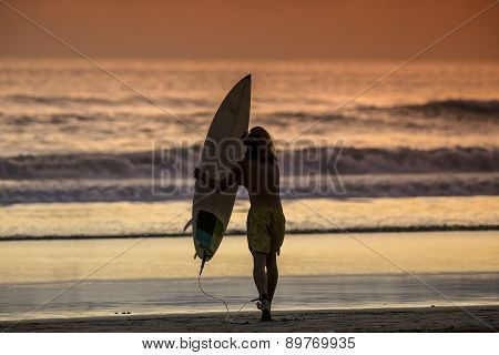 Surfer On The Beach At Sunset Tme