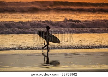 Surfer On The Beach At Sunset Tme
