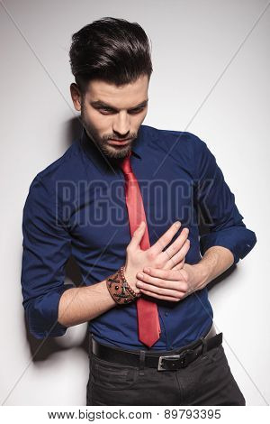 Young business man looking down while holding his hands together.