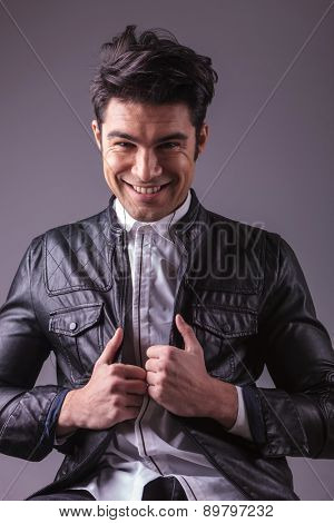 Haapy young fashion man smling to the camera while pulling his jacket.