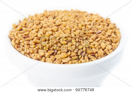 Fenugreek seeds in white bowl on white background