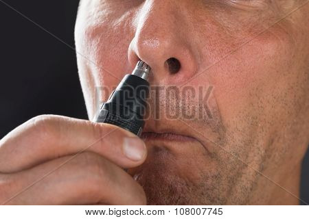 Man Removing Hair From His Nose With Trimmer
