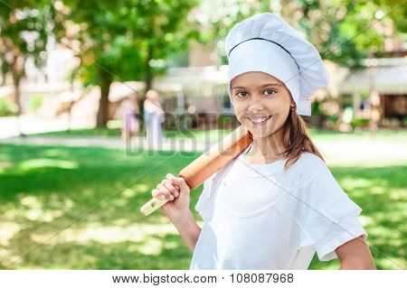 Happy little chef with a wooden rolling-pin.