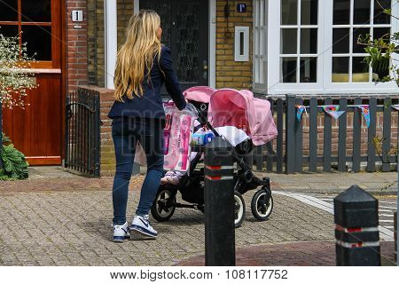 Young Woman With Twins Pram Walking Along A Street In Zandvoort, The Netherlands