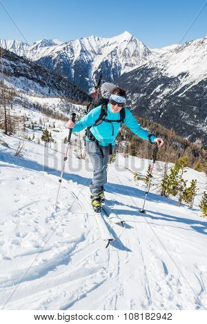 Young woman ascending a slope on skis.