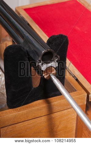 Cleaning an over/under style shotgun, inserting the brush on the cleaning rod into the lower chamber from the breach end