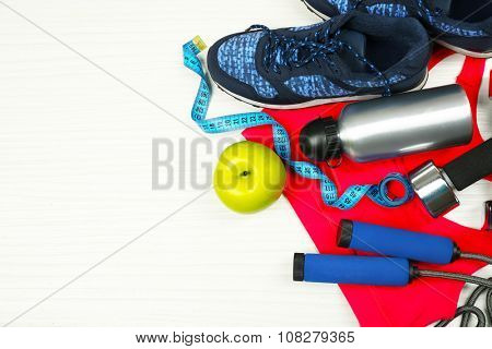 Sport clothes, shoes and sport equipment on light background