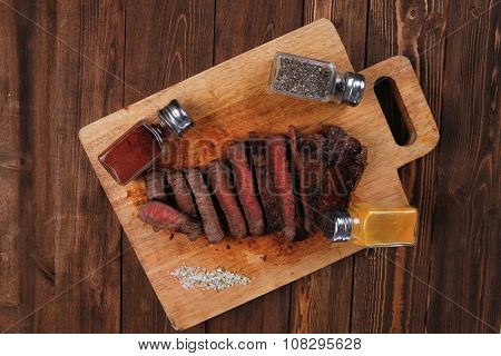 fresh roast red beef meat fillet mignon cutted on wooden plate with many different kinds of dry spices red hot paprika crushed black pepper salt dry mustard grains over table