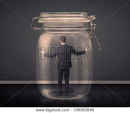 Businessman trapped into a glass jar concept on background