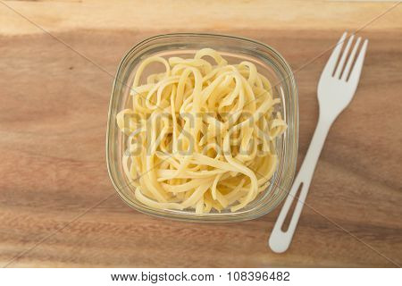 a small portion of linguini pasta in a glass storage container