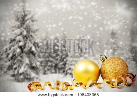 Golden Christmas decorations in the snow, snow cowered pine trees in the background