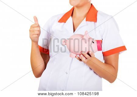 Young beautiful female doctor or nurse holding a piggybank.