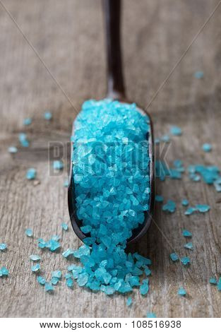 Light blue salt in a spoon on old wooden board.
