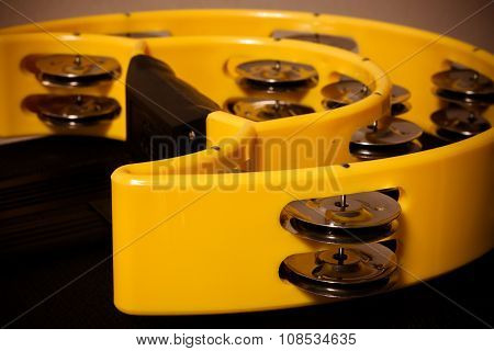 the single yellow tambourine on black background.
