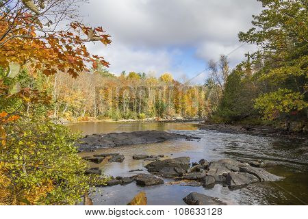 River Winding Through A Forest In Autumn