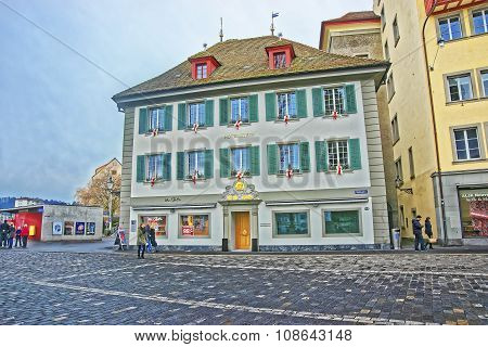 LUCERNE SWITZERLAND - JANUARY 04 2015: Unidentified people passing by an elegant building with bright green shutters at picturesque square Muhlenplatz in Lucerne Switzerland