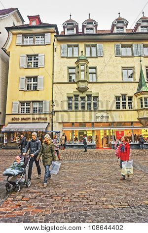 LUCERNE SWITZERLAND - JANUARY 04 2015: Young and attractive couple walking with a baby pram along picturesque square Muhlenplatz in Lucerne Switzerland