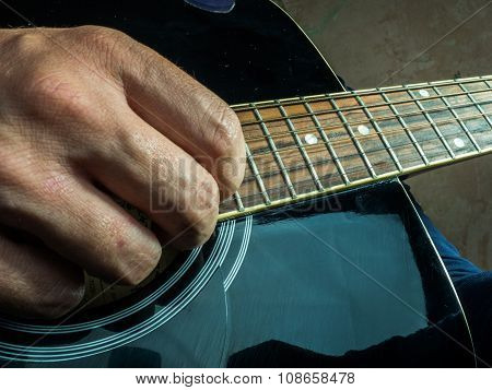 Closeup photo of an acoustic guitar played by a man.