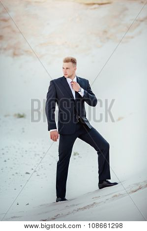Fashionable young man in the sand pit. Blonde hair