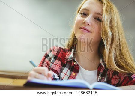 Smiling student writing on notebok at the university