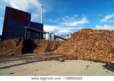 Bio Power Plant With Storage Of Wooden Fuel Against Blue Sky