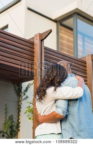Back view of couple with arms above after buying house