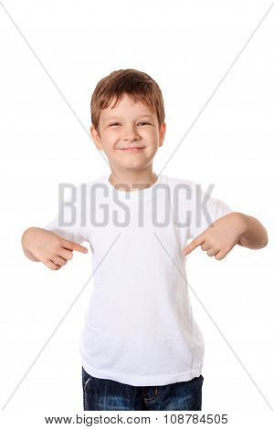 Happy Little Boy Pointing His Fingers On A Blank T-shirt, A Place For Your Advertising.