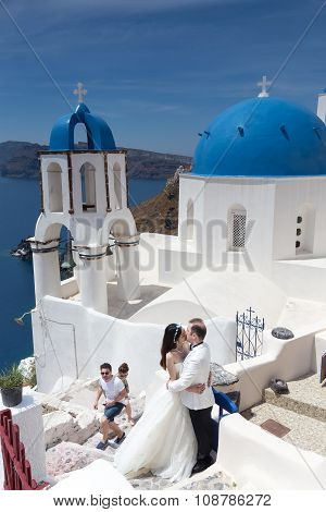 A Couple Of Newlywed’s Tourists In Front Of Church With The View Of Santorini Island, In Greece. Tou
