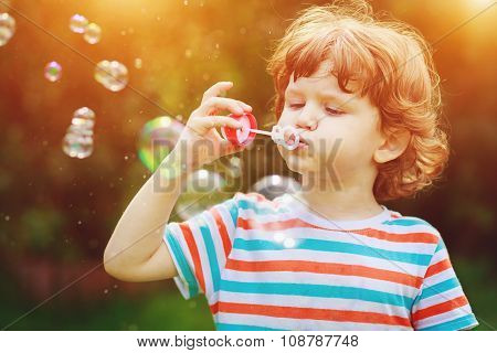 Child Blowing Soap Bubbles In Summer Park.