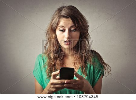 Spellbound girl staring at her phone