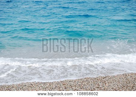transparent deep blue wave of the sea that breaks on the shore with white foam and sand for summertime