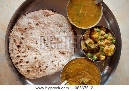 Traditional Indian food vegetarian roti served in small bowls on a round tray.