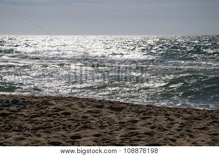 At the beach with waves in the sea sea with reflections from the sun
