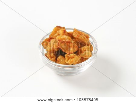 bowl of salty pork greaves on white background
