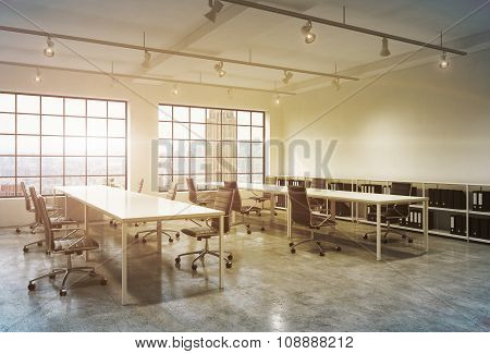 Workplaces In A Bright Sunset Loft Open Space Office. Empty Tables And Docents' Book Shelves. New Yo