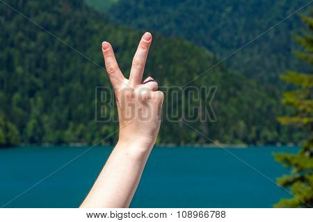Peace sign on the background of a mountain lake