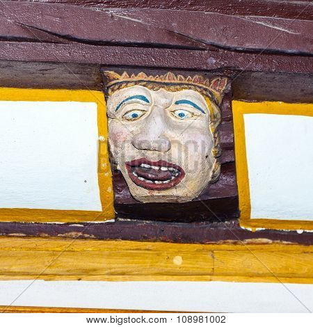 Wood Carving With Funny Faces On Timber Balk  Of Old Framework Houses