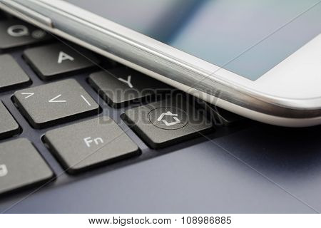 A White Mobile With Reflection On A Keyboard With Home Button