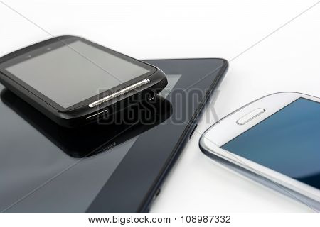 Black Smartphone On Black Tablet With White Mobile Besides