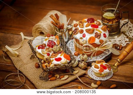 Traditional Easter cake with decorations and cupcakes on wooden table