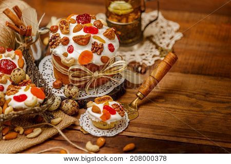 Traditional Easter cake with decorations and cupcakes on wooden table
