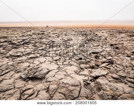 People walking across mineral soil formations around lake Dallol in Danakil Depression Ehtiopia